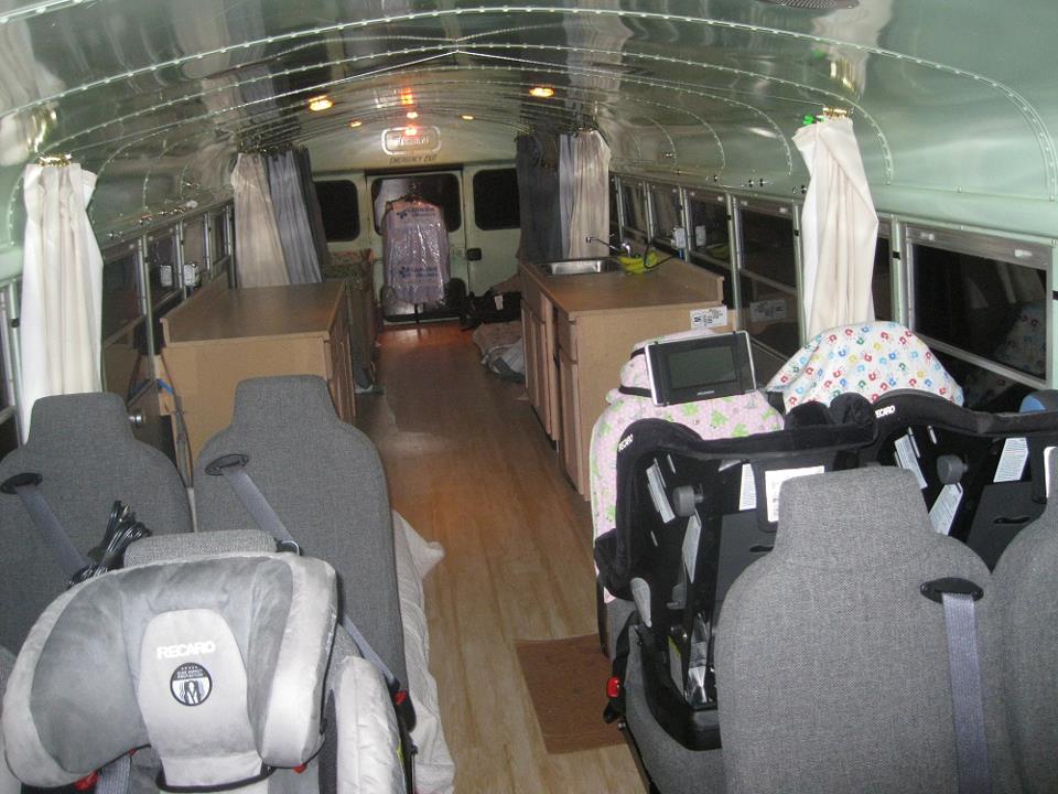 View from front of bus looking rearward.  Seats and car seats in the foreground